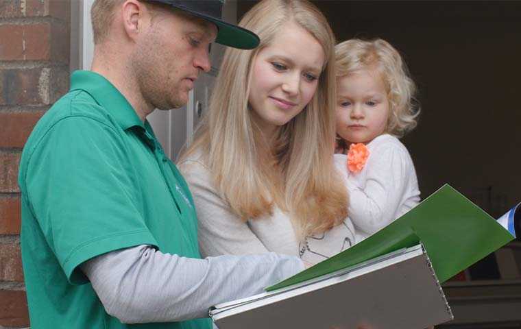 tech explaining services in a brochure to a mother and child in doorway of their home